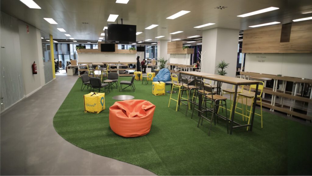 Sala de descanso en la oficina central de Glovo Delivery con puff, cojines y decoración moderna.