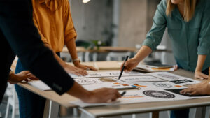 Grupo de diseñadores trabajando en diferentes logotipos sobre una mesa en un entorno de oficina.