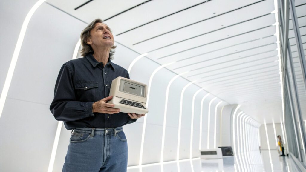 Hombre mayor sosteniendo una computadora Apple vintage en un entorno moderno, representando la evolución e historia del valor de la marca Apple.